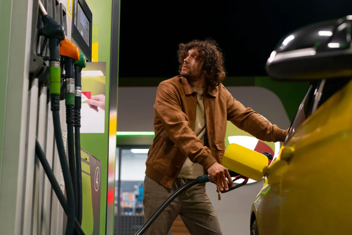 Persona cargando combustible en una gasolinera iluminada